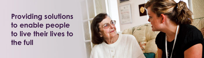 Image of an elderly woman and support worker talking with the caption "Providing solutions to enable people to live their lives to the full"